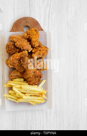 Fastfood: Gebratene Hähnchenschenkel, würzige Flügel, Pommes frites und Chicken Streifen über weiße Holz- Hintergrund, Ansicht von oben. Flach, Overhead, von oben. Cop Stockfoto