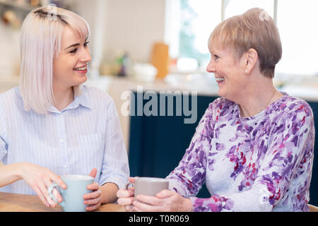 Junge Frau die Zeit zu Besuchen ältere Nachbarin und Sprechen Stockfoto