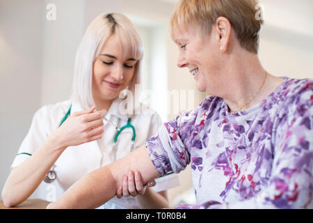 Weibliche Krankenschwester, die ältere Frau Injektion in Arm mit Spritze Stockfoto