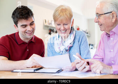 Junge Mann hilft Senior Paar mit finanziellen Schreibarbeit zu Hause Stockfoto
