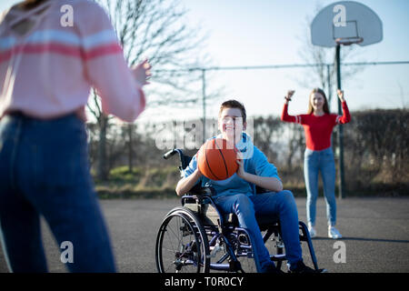 Teenager im Rollstuhl Basketball spielen mit Freunden Stockfoto