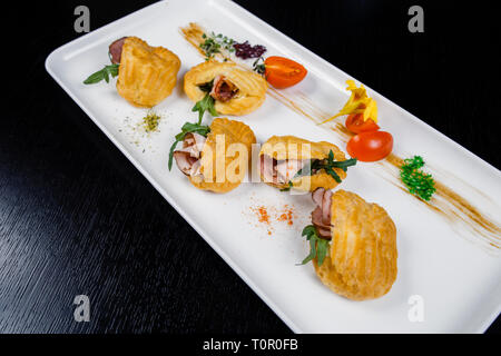 Mousse von Käse mit Speck in Eclair, serviert auf einem Teller und bedeckt mit grünen und Tomate cherry Stockfoto