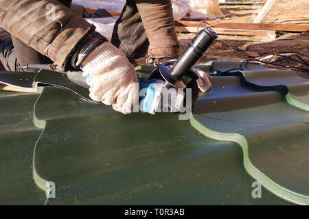 Der Master schneidet eine professionelle Blech für die Installation auf dem Dach des Hauses 2019 Stockfoto