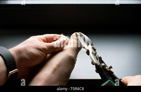 Man clipping Zehennägel mit Blech Scheren Stockfoto