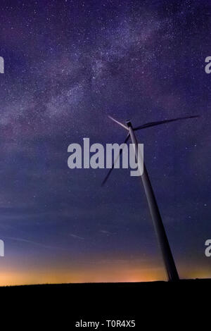 Eine Windkraftanlage mit schönen Milchstraße im Hintergrund mit hellen Sterne über flaches Land um Mitternacht Stockfoto