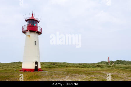 Leuchtturm List-West innerhalb einer Dünenlandschaft mit Gras und Sand. Aussicht an einem klaren Tag. In List auf Sylt, Schleswig-Holstein, Deutschland Stockfoto