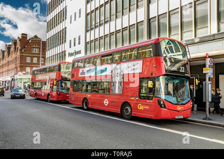 Zwei Londoner Doppeldeckerbusse an der Kings Road an einer Bushaltestelle vor dem Peter Jones Kaufhaus in Sloane Square, London, Großbritannien Stockfoto