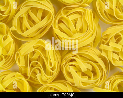 Ungekocht gelb italienische Pasta tagliatelle Nester Textur Top View close-up Stockfoto