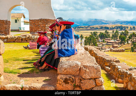 Eine Gruppe von peruanischen Quechua indigene Frauen sitzen auf einer alten Inka Wand im archäologischen Inka Ruine von Chinchero, Cusco Region, Peru. Stockfoto
