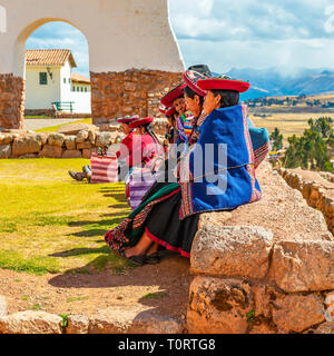 Eine Gruppe von peruanischen Quechua indigene Frauen sitzen auf einer alten Inka Wand im archäologischen Inka Ruine von Chinchero, Cusco Region, Peru. Stockfoto