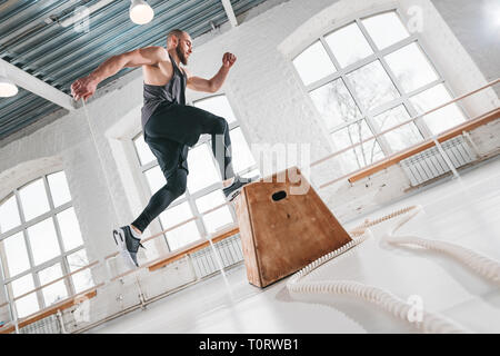 Starke Mann tut einem Kasten springen Übung im Fitnessraum. Männliche Athlet mit Box für die Übungen Stockfoto