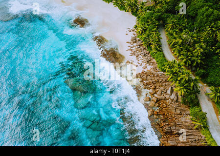Seychellen Mahe Island Luftbild Drohne Landschaft der Küste Paradies Sandstrand mit Palmen und Schöne, klare blaue Meer Wellen gegen Wegrollen Stockfoto