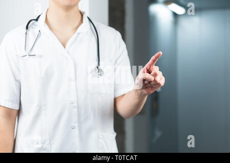 Helle Nahaufnahme von männlicher Arzt in Uniform mit Stethoskop zeigenden Finger in der Luft. Kopieren Sie Platz oder grafischen Raum Stockfoto
