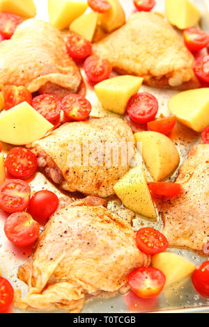 Erfahrene Hühnerteile mit Yukon Gold Kartoffeln und Tomaten auf ein Blatt pan, vertikale Ansicht Stockfoto