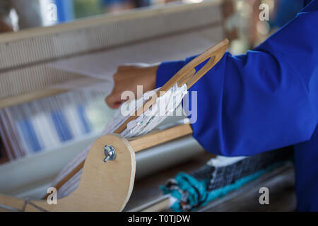 Junge Frau spinnt ein weißes Tuch auf einer Hand Holz Webstuhl. Traditionelle russische Volkskunst Stockfoto
