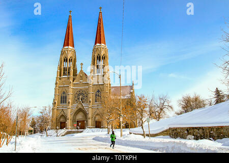 Runner schützen Sie sich vor der Kälte führt die Straßen der Stadt vor der Kathedrale von Saint Helena, Helena, Montana, USA Stockfoto