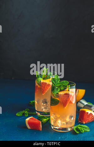 Grapefruit und Minze Gin Tonic Cocktail, einen erfrischenden Drink mit Eis. Kalten Sommer Citrus erfrischenden Drink Cocktail oder Getränk mit Eis auf dunklem Blau conc Stockfoto