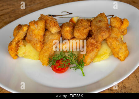 Panierte weißen Fisch. Mit Kartoffelpüree, Cherry Tomaten garniert, Stiele Dill und Scheibe der Zitrone. Stockfoto