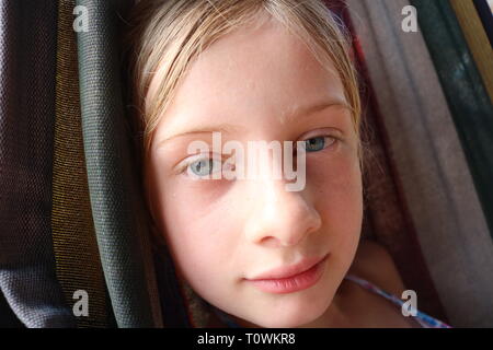 Portrait einer jungen Nasse blonde Mädchen mit blauen Augen zufrieden ruht in einer Hängematte Stockfoto