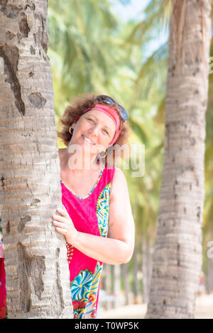 Porträt eines lächelnden gerne ältere Frau, die in der Nähe der Palme. Stockfoto