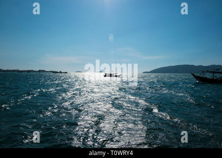 Fischerboote in Silhouette auf das Südchinesische Meer mit einer Sonne Spike, Reflexion in Kota Kinabalu, Sabah, Borneo, Malaysia. Stockfoto