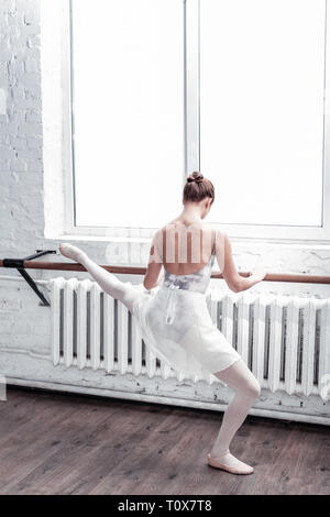 Angenehme schöne Ballerina stehend in der Nähe der Fenster Stockfoto