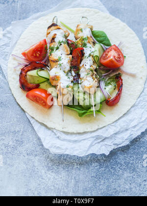 Gegrilltes Hähnchen auf Metall Spieße mit griechischen Soße und frischem Gemüse auf der Pita. Griechische Küche. Stockfoto