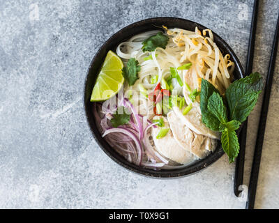 Traditionelle vietnamesische Suppe-Pho Ga in schwarz Schüssel mit Huhn und Reis Nudeln, Minze und cilantro, grüne und rote Zwiebel, Paprika, Sojasprossen und Kalk Stockfoto