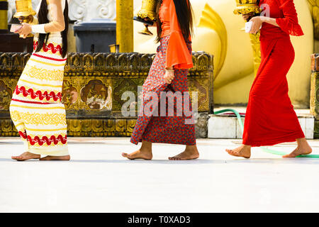 (Selektive Fokus) Einige birmanischen buddhistischen Gläubigen sind barfuss Um die Shwedagon Pagode, das Tragen eines traditionellen und farbenfrohen Longyi. Stockfoto