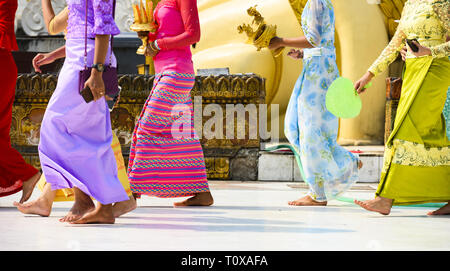 (Selektive Fokus) Einige birmanischen buddhistischen Gläubigen sind barfuss Um die Shwedagon Pagode, das Tragen eines traditionellen und farbenfrohen Longyi. Stockfoto