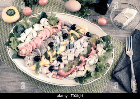 Ein beliebtes Gericht der amerikanischen Küche - Cobb Salat, bestehend aus grünen, Eier, Tomaten, Käse, Fleischwaren, in Reihen gestapelt auf eine große Schüssel und poure Stockfoto