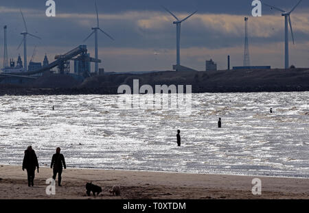 Leute gehen mit ihren Hunden am Crosby Beach in Merseyside neben Anthony's Gormley" an einen anderen Ort "eisernen Männer Skulpturen. Stockfoto