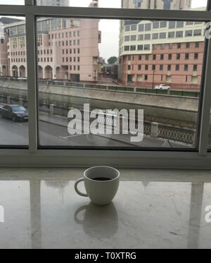 Weiße Tasse Kaffee auf das Fenster mit stadtbild Hintergrund. Stockfoto