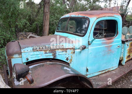 Eine alte Dodge Power Wagon truck schmilzt in die Erde und unterstützt sogar ein Kaktus im Lastwagenbett wachsende Stockfoto