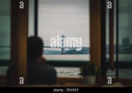 Die George Washington Brücke überquert den Hudson River von Manhattan mit New Jersey wie durch ein Fenster auf einem Boot mit einem Touristen genießen den Blick auf ein dunstiger Herbst Tag gesehen. Stockfoto