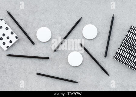 Leere Abzeichen und scharfe schwarze Bleistifte auf grauem Beton Hintergrund. Stockfoto