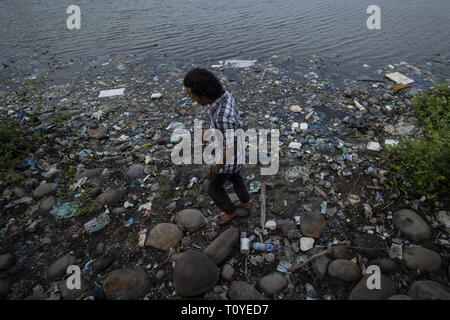 März 22, 2019 - Lhokseumawe, Aceh, Indonesien - ein Bewohner gesehen zu Fuß auf den Rand eines Reservoir kontaminierten mit Kunststoffabfällen in Lhokseumawe, Provinz Aceh, Indonesien. . Auf der Grundlage der Datensätze 25 Fälle von marinen Biota in Indonesien durch macroplastic Abfälle und Mikroplastik Abfälle aus menschlichen Aktivitäten betroffen waren. Und von Greenpeace Indonesien Daten, Abfallerzeugung in Indonesien erreicht 65 Millionen Tonnen pro Jahr 10,4 Mio. Tonnen oder 16 Prozent ist aus Kunststoff. (Bild: © zikri Maulana/SOPA Bilder über ZUMA Draht) Stockfoto