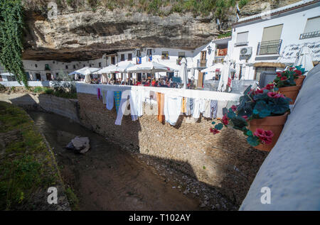 Setenil, Spanien - 4. März, 2019: Straße mit Wohnungen in Felsen Überhänge gebaut. Setenil de las Bodegas, Cadiz, Andalusien, Spanien. Sonnige höhlen Nachbarschaft Stockfoto