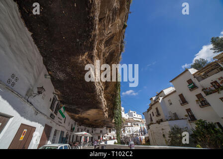 Setenil, Spanien - 4. März, 2019: Straße mit Wohnungen in Felsen Überhänge gebaut. Setenil de las Bodegas, Cadiz, Andalusien, Spanien. Restaurant des sonnigen Höhlen Stockfoto