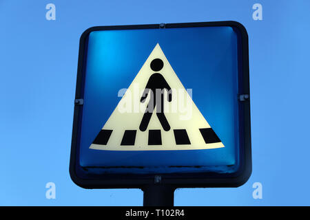 Blaue und weiße crosswalk Zeichen leuchtet auf einem klaren Himmel Stockfoto