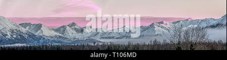 Panorama von einem rosafarbenen Sonnenuntergang über die schneebedeckten Berge in der Nähe des Knik River von Alaska. Stockfoto