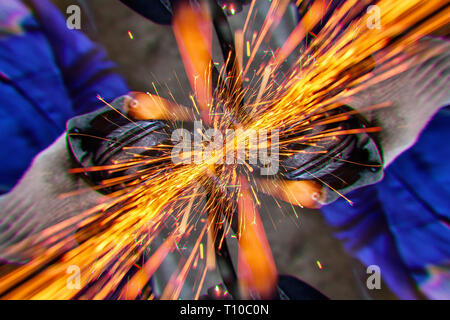 Eine Nahaufnahme von einem Automechaniker mit einem Metall Grinder ein Auto in eine Werkstatt zu schneiden, helle Blitze fliegen in verschiedene Richtungen, in die Stockfoto