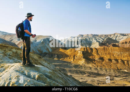 Traveler Kerl steht am Rande eines Hügels auf dem Hintergrund einer Wüste Berg Landschaft. Nationalpark Altyn-Emel. Kasachstan Stockfoto