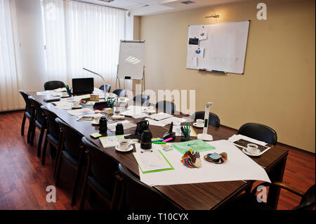 Moderne Business Office Interior mit Tischen und Stühlen, Laptop, Kamera und Bürobedarf ohne Beschäftigte. Stockfoto