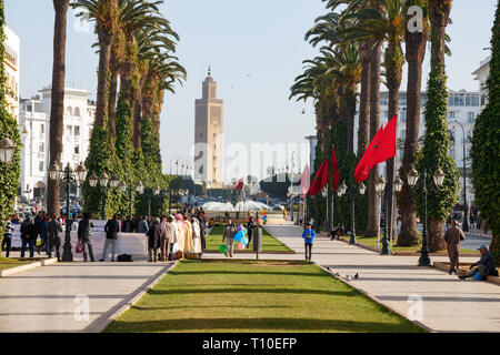 Blick auf die Avenue Mohammed V, mit Palmen, nicht identifizierte Personen und die Assounna Moschee Tower. Rabat Marokko. Stockfoto