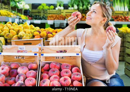 Froh, dass positive bezaubernde Frau Kunde auswählen Pfirsiche auf Obst Markt Stockfoto
