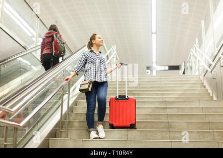 Portrait von attraktives Mädchen, die Treppe in der Nähe der u-Bahn mit roten Koffer Stockfoto