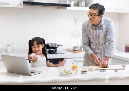 Gerne kleine Mädchen und Großvater Plätzchen backen in der Küche Stockfoto