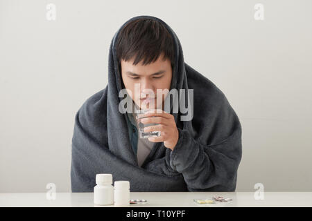 Ein Mann in einer warmen Decke sonnt sich auf einem hellen Hintergrund gewickelt Stockfoto