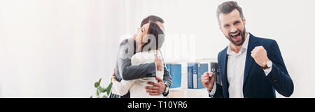 Kollegen, umarmten sie lächelnd und Feiern im Büro Stockfoto